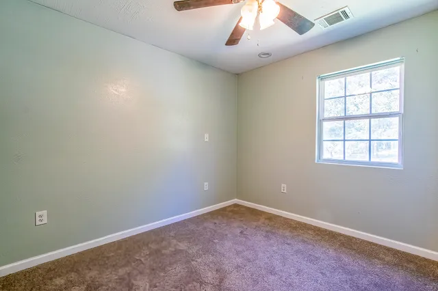 an empty room with a ceiling fan and window