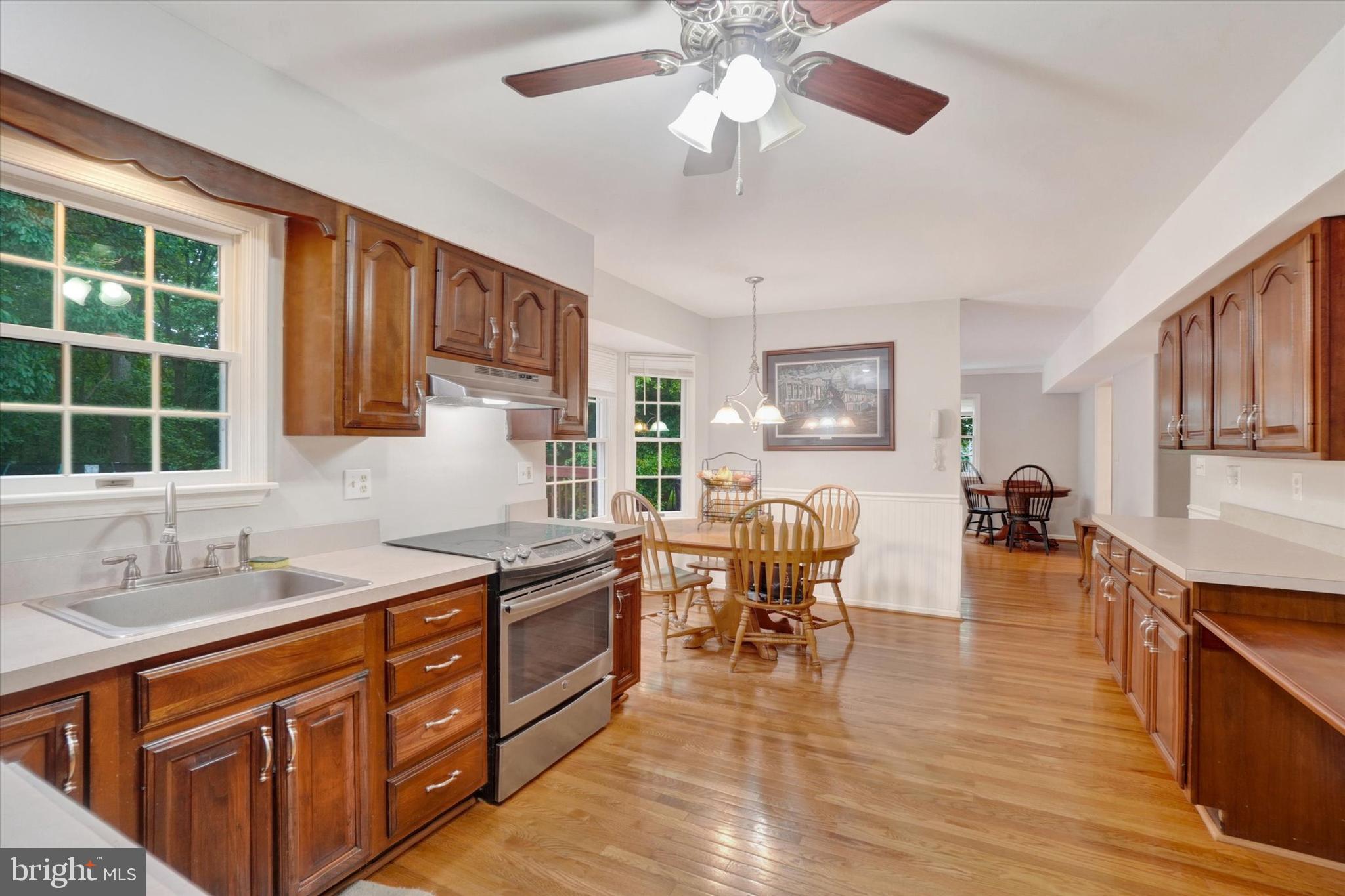 5677 Woods Road Stewartstown, PA 17363 - Photo 8 of 26 a kitchen with stainless steel appliances granite countertop a sink dishwasher stove and wooden cabinets with wooden floor