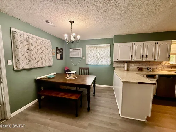 a room with kitchen island a wooden floor and a view of kitchen