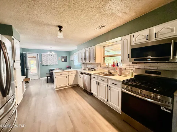 a kitchen with granite countertop a stove top oven a sink dishwasher a dining table and chairs with wooden floor