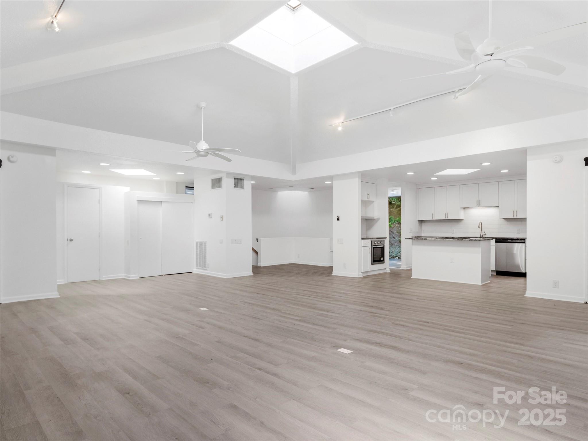 141 Wildflower Road Spruce Pine, NC 28777 - Photo 15 of 22 an empty room with wooden floor and kitchen view