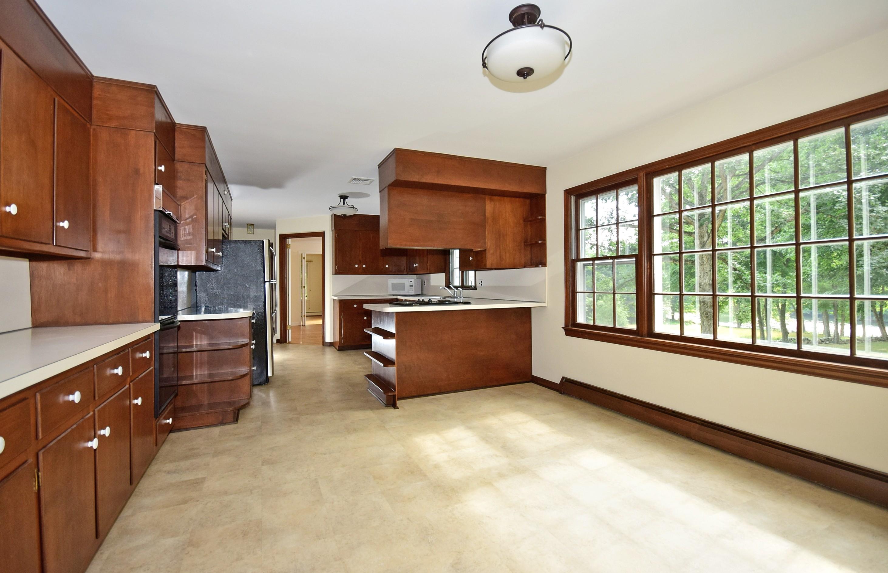 1342 Valley Road New Canaan, CT 06840 - Photo 5 of 10 a large kitchen with stainless steel appliances a large counter top a stove a chimney a sink and cabinets