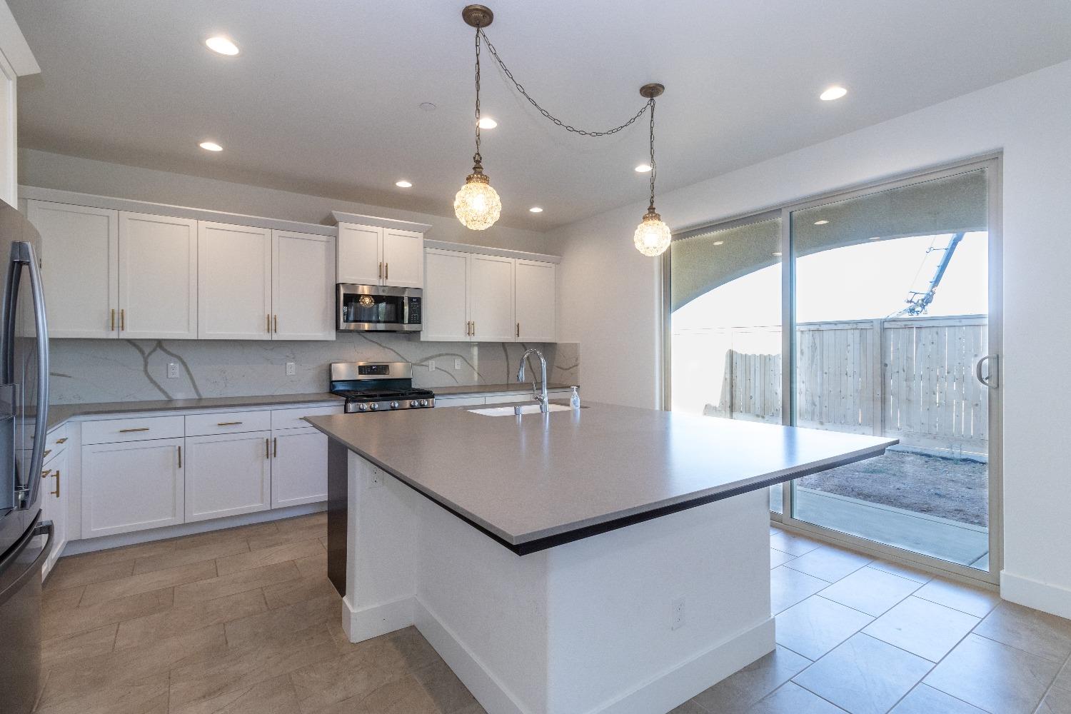 4344 Oak Knoll Road Madera, CA 93636 - Photo 10 of 33 a kitchen with kitchen island granite countertop a stove a sink a oven and a refrigerator with wooden floor