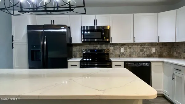 a kitchen with a stove a chandelier and a wooden floor