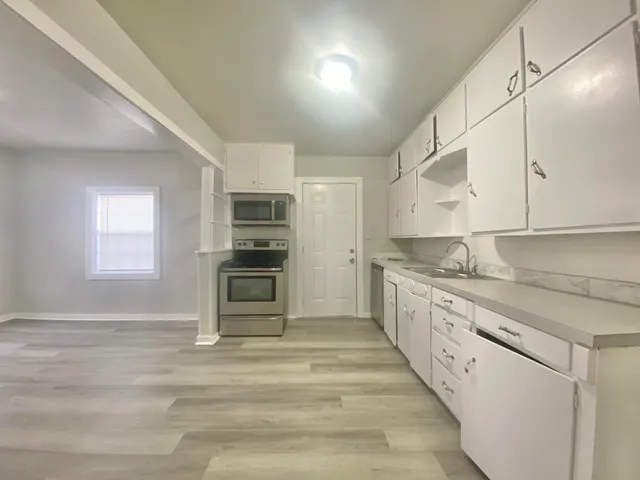 a large kitchen with granite countertop a stove and a sink