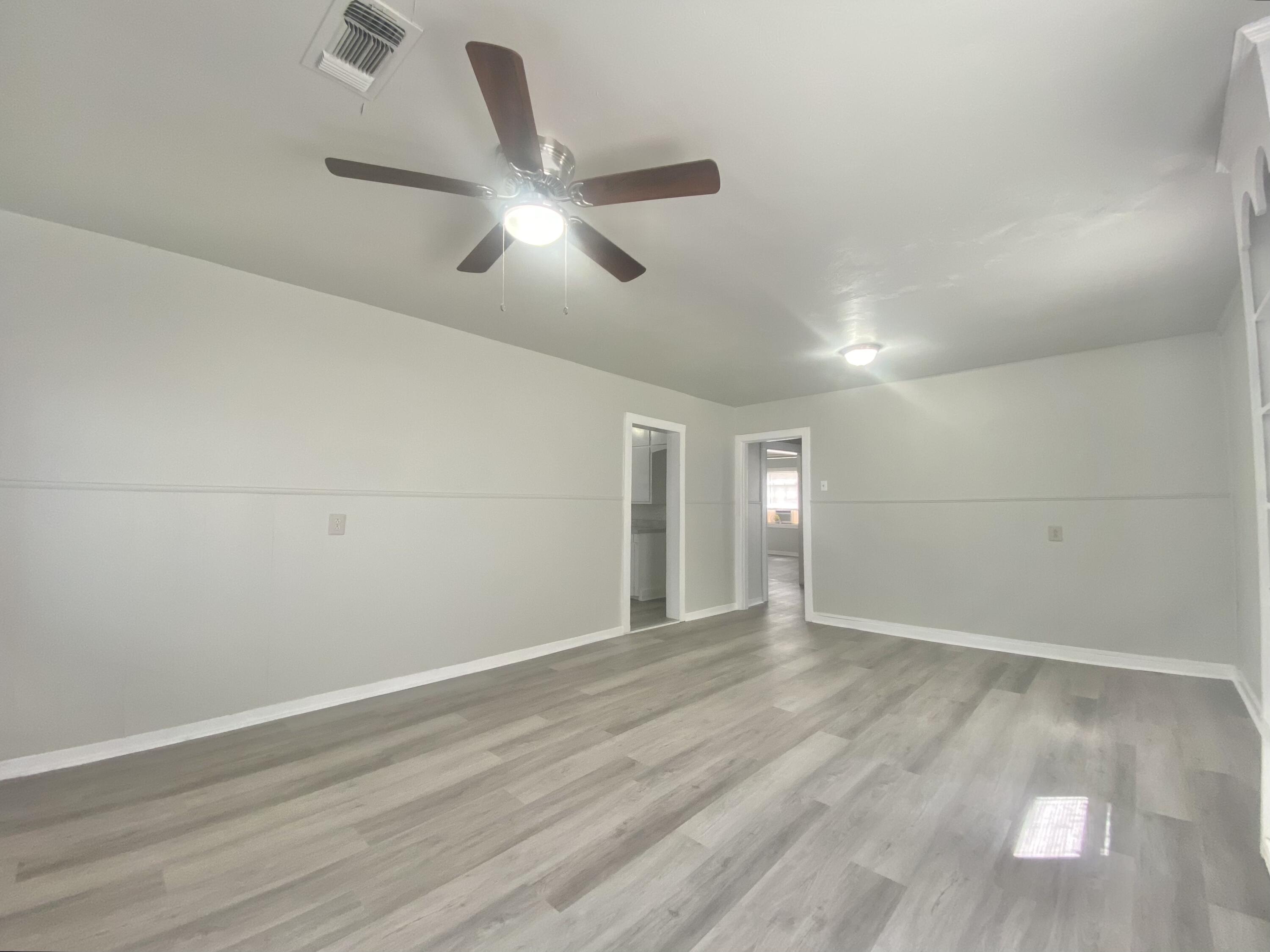 5701 45th Street Lubbock, TX 79414 - Photo 8 of 12 an empty room with wooden floor fan and windows