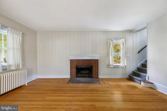 a view of empty room with wooden floor and fireplace