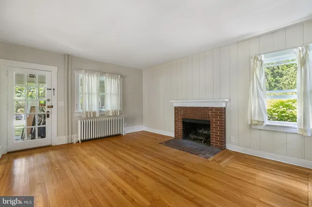 an empty room with wooden floor fireplace and windows
