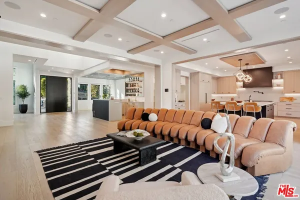 a kitchen with stainless steel appliances kitchen island granite countertop a sink a stove a dining table and chairs with wooden floor