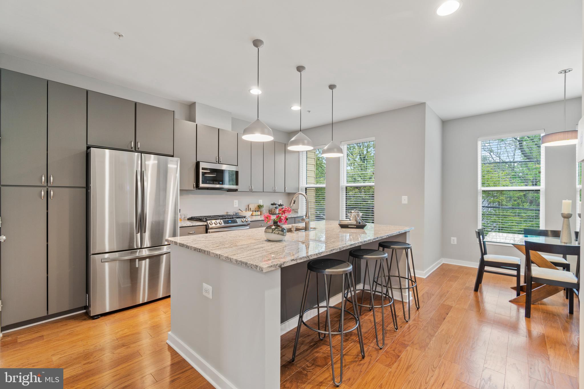 a kitchen with stainless steel appliances a table chairs refrigerator and wooden floor