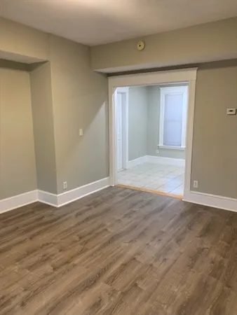 a view of an empty room and wooden floor and closet