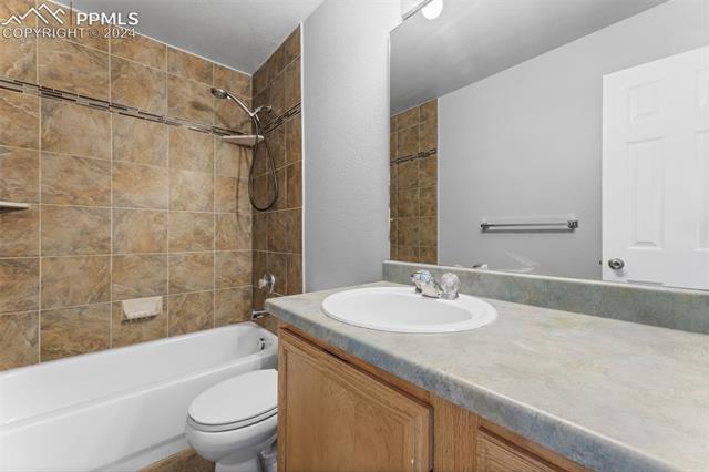 7515 Farmcrest Road Colorado Springs, CO 80925 - Photo 21 of 40 Full bathroom featuring vanity, tiled shower / bath combo, and toilet
