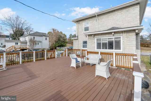 a backyard of a house with wooden deck table and chairs