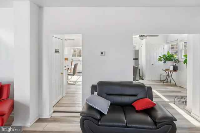 a view of a white house next to a yard with big trees