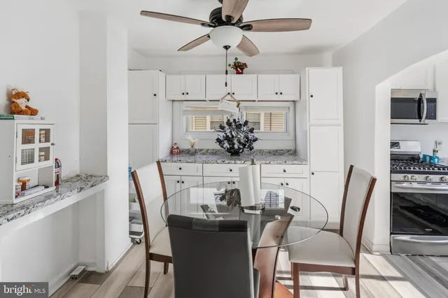 a kitchen with granite countertop white cabinets white appliances sink and chairs