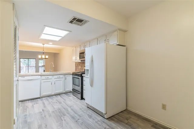 a kitchen with a refrigerator a sink and dishwasher with wooden floor