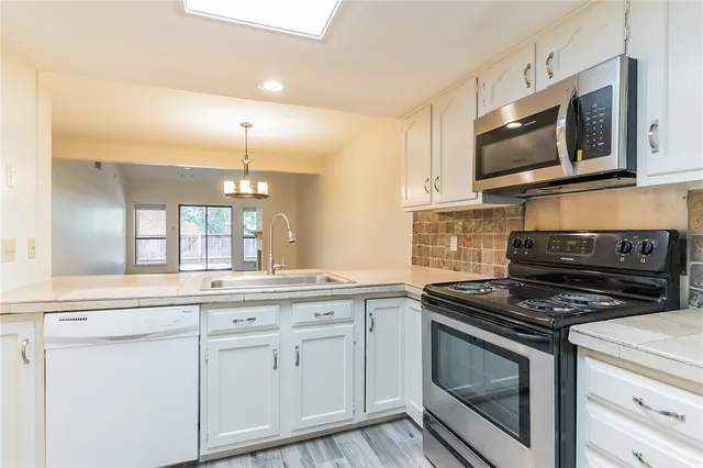a kitchen with white cabinets stainless steel appliances and sink