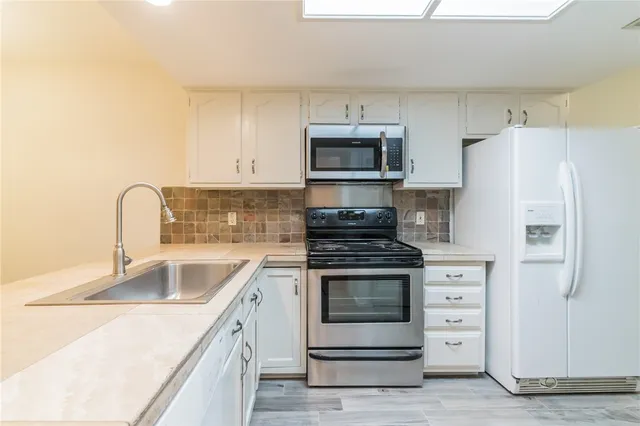 a kitchen with white cabinets and stainless steel appliances
