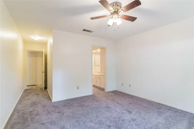 an empty room with chandelier fan and windows