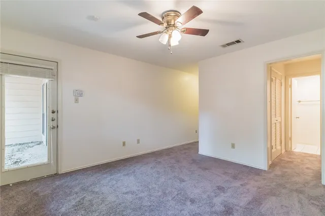 an empty room with a chandelier fan and windows