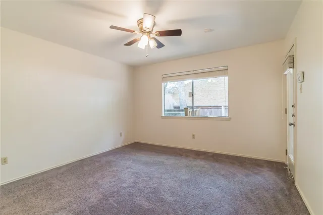 an empty room with a window and a fan