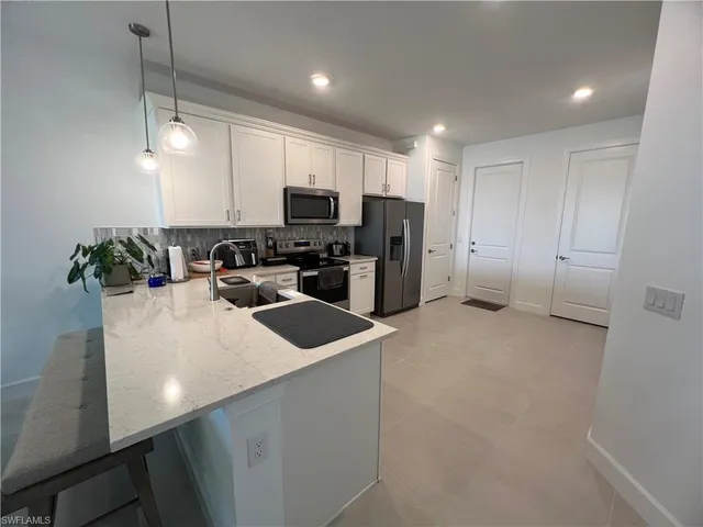 a kitchen with kitchen island a white counter top space cabinets and stainless steel appliances