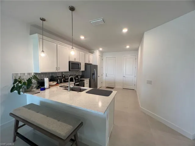 a large kitchen with sink a refrigerator and chairs