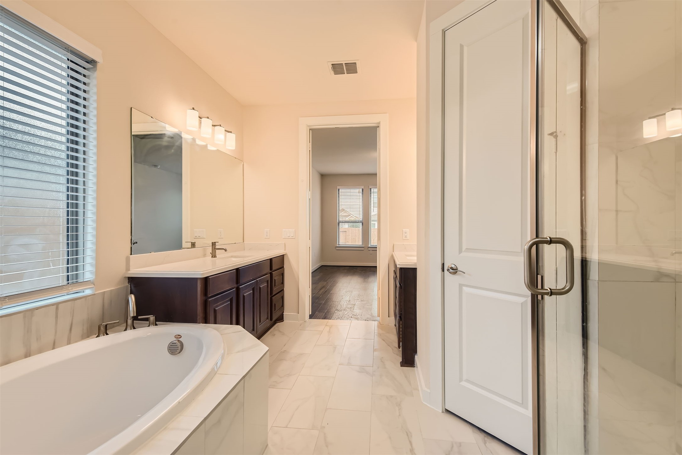 8313 Spire View Austin, TX 78744 - Photo 17 of 33 Indulge in a tranquil primary bathroom featuring a soaking tub, dual vanities, and a separate glass-enclosed shower.