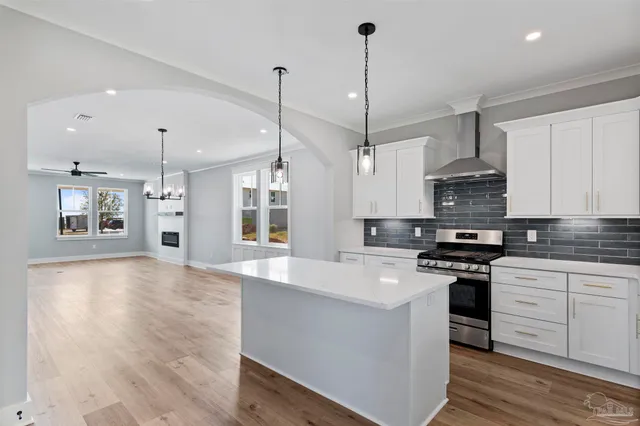 a kitchen with stainless steel appliances kitchen island granite countertop a stove a sink and white cabinets with wooden floor