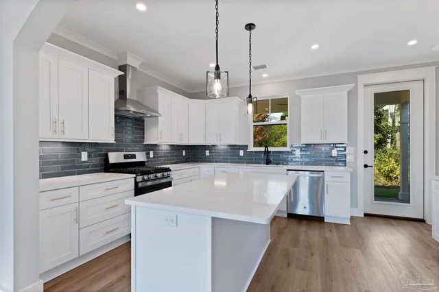 a kitchen with stainless steel appliances granite countertop a stove a sink and white cabinets with wooden floor