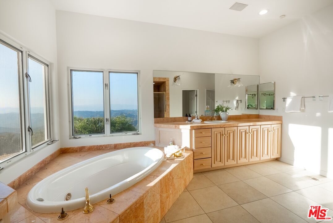 21965 Saddle Peak Road Topanga, CA 90290 - Photo 22 of 56 a bathroom with a tub a sink a mirror and a shower