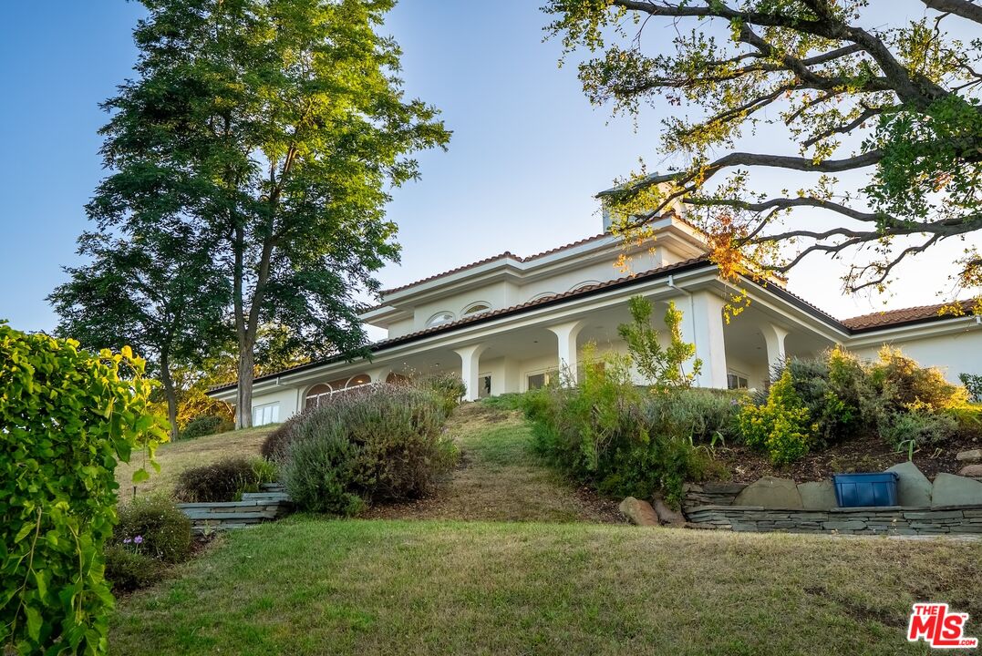 21965 Saddle Peak Road Topanga, CA 90290 - Photo 51 of 56 a front view of a house with a yard and potted plants