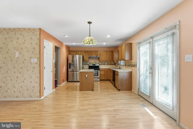 a view of a kitchen with kitchen island stainless steel appliances a refrigerator cabinets and a sink
