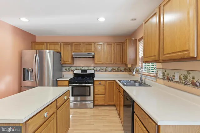 a kitchen with a sink a counter top space stainless steel appliances and cabinets