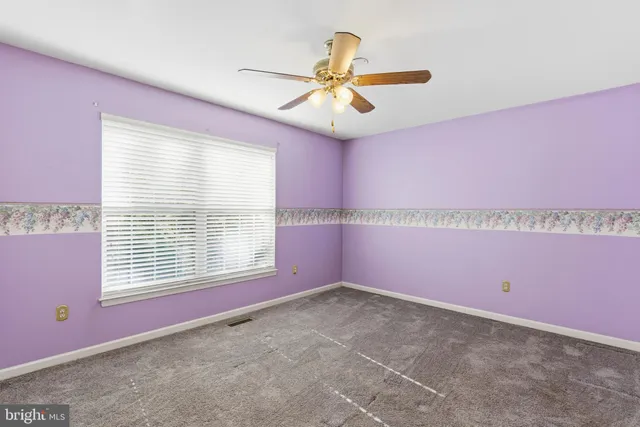 a view of empty room with window and a ceiling fan