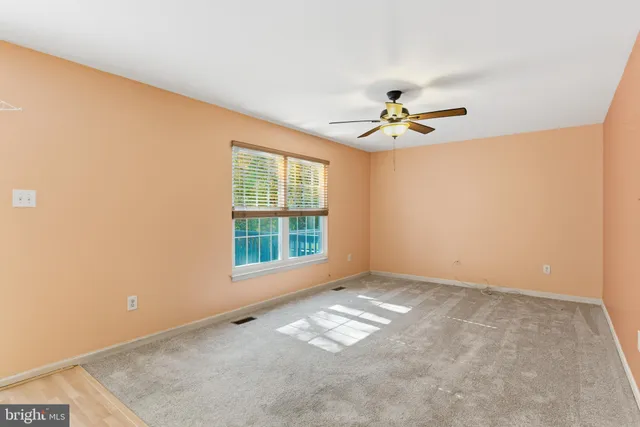an empty room with windows and ceiling fan