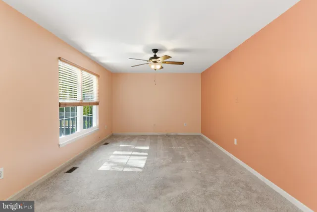 an empty room with windows and ceiling fan