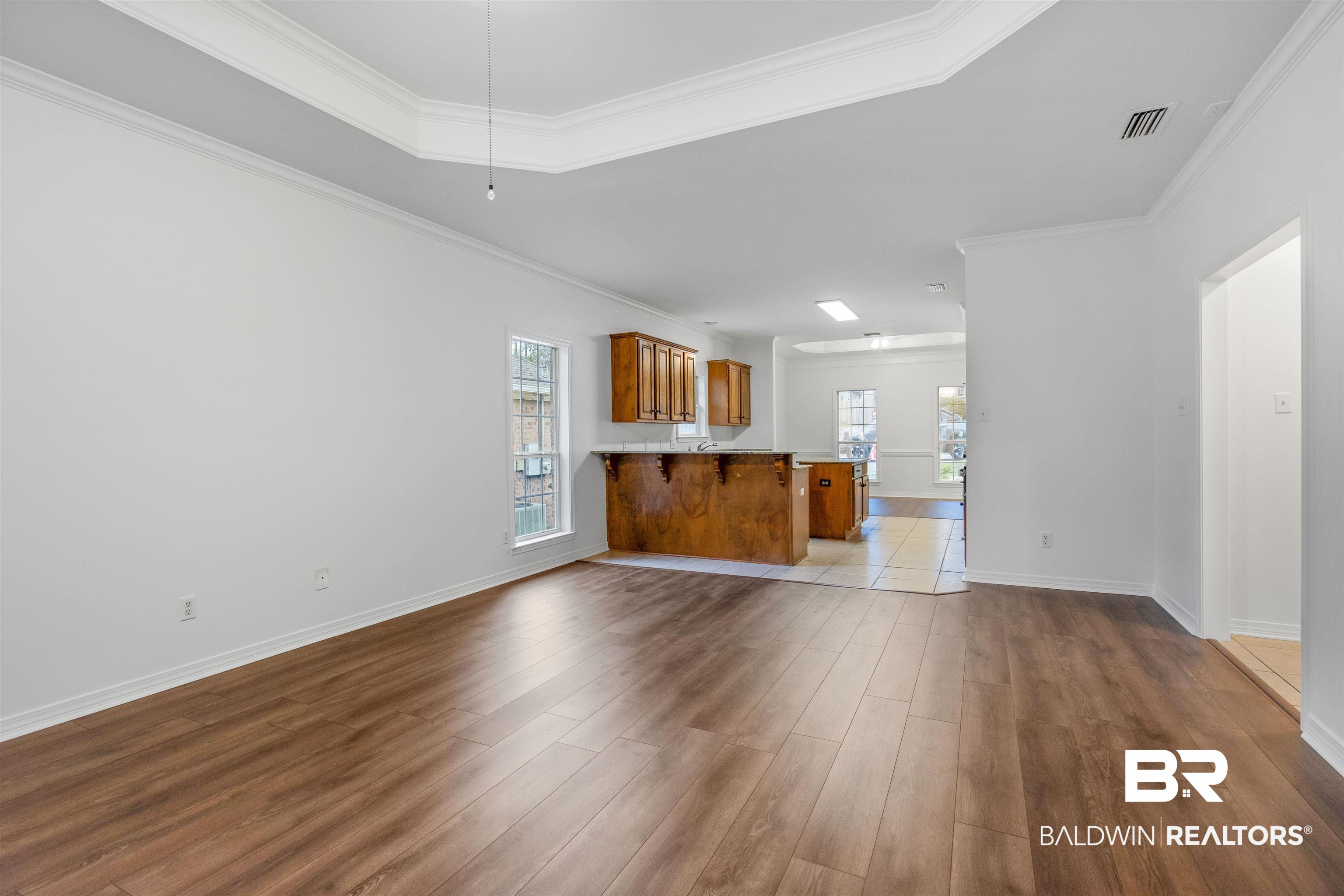 1007 Linlen Avenue Mobile, AL 36609 - Photo 5 of 21 Unfurnished living room with light hardwood / wood-style floors, a raised ceiling, and ornamental molding