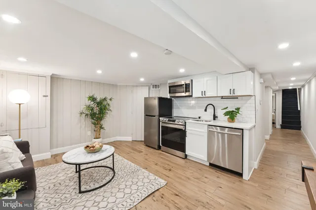 a kitchen with stainless steel appliances a stove a sink a refrigerator and a dining table