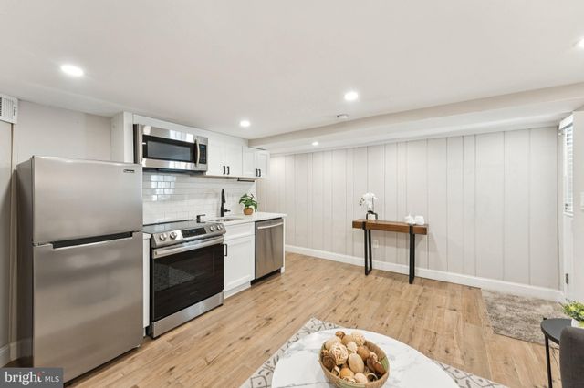 a kitchen with kitchen island a counter top space a sink stainless steel appliances and cabinets