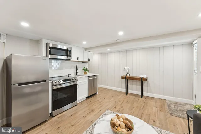 a kitchen with kitchen island a counter top space a sink stainless steel appliances and cabinets