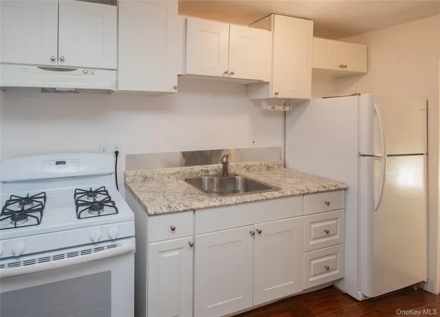 a kitchen with granite countertop white cabinets and sink
