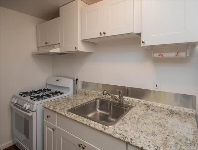 a kitchen with granite countertop a sink a stove and cabinets
