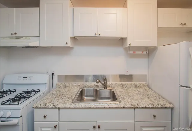 a kitchen with granite countertop white cabinets and a stove