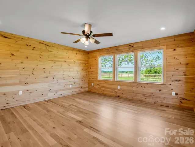 a view of empty room with wooden floor and fan
