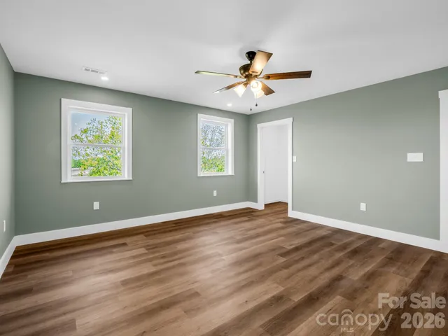 a view of an empty room with window and wooden floor