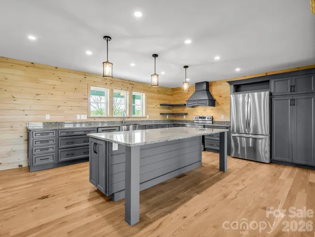 a large kitchen with a large counter top stainless steel appliances and wooden floor