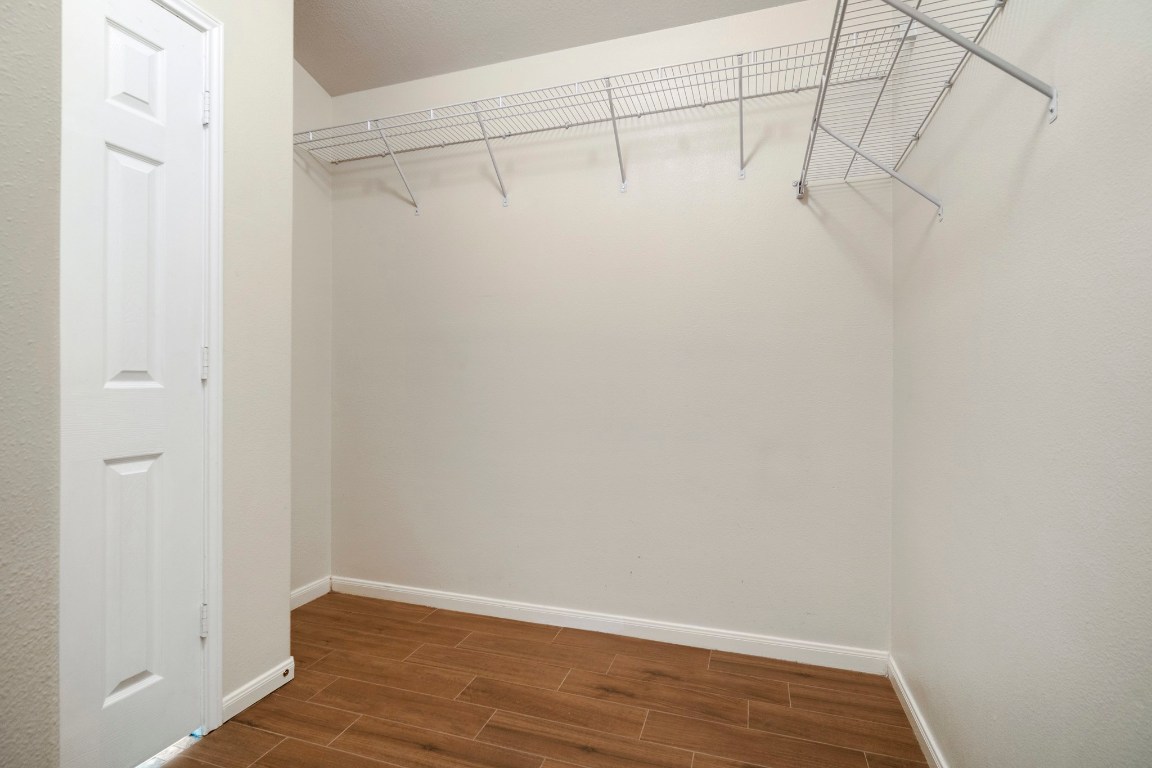 615 Timberstand Lane Spring, TX 77373 - Photo 16 of 19 Discover the spacious primary walk-in closet, featuring sleek shelving and inviting hardwood floors, perfect for organizing your wardrobe in style.