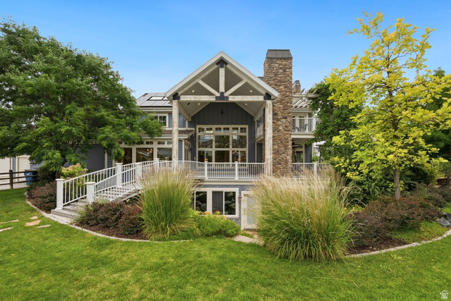 672 Perry Hollow Drive Mapleton, UT 84664 - Photo 100 of 106 Rear exterior featuring multiple levels, an elevated deck with white railings, a stone chimney, extensive glass panels, and mature landscaping