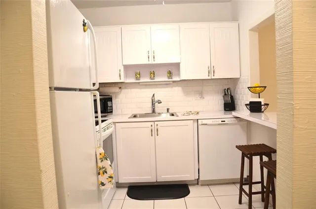 a kitchen with a refrigerator a stove a sink and white cabinets with wooden floor